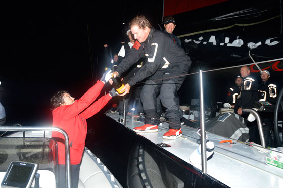 Welcome to Bermuda! COMANCHE skipper Ken Read accepts a bottle of champagne from Leatrice Oatley, Commodore of the Royal Bermuda YC after the 100ft raceer crossed the finish line at  4:22:53EDT to set a new elapsed  time  record of 34h 52m 53s.  This broke the previous record set by RAMBLER IN 2012  by 4h 56mins. Photo: Barry Pickthall/PPL