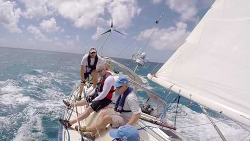 Captain Dale Fitch, foreground, Jon Burns, middle, and Jacques Soumis crouched, positioning to the high side going upwind. Notice all the “cruising” gear: wind generator, solar panels, radar mount with satellite antennas and GPS on the aft of the boat. This is the type of boat which should be in the Lottery Class.